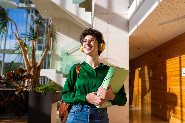 Estudante com fones de ouvido e cadernos, em imagem do EAD da Anhembi Morumbi